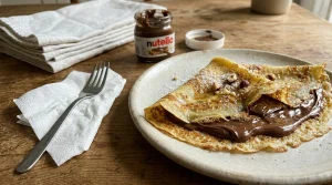 Crêpe garnie de Nutella et amandes sur assiette blanche