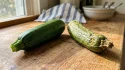 Une courgette fraîche et une courgette pourrie sur une planche.
