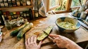 Mains préparant des courgettes tranchées dans une cuisine rustique.